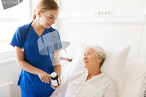Image of nurse giving medicine to senior woman at hospital