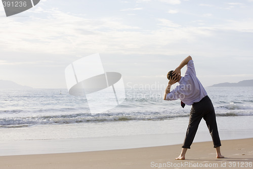 Image of Businessman doing exercises on beach