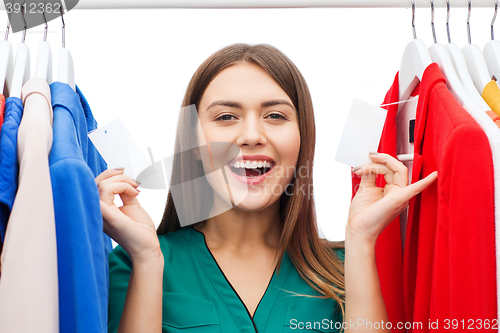 Image of happy woman with sale tags on clothes at wardrobe