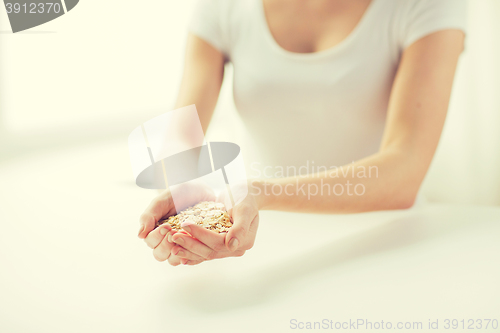 Image of close up of woman hands holding oatmeal flakes