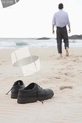 Image of Businessman walking barefoot on beach