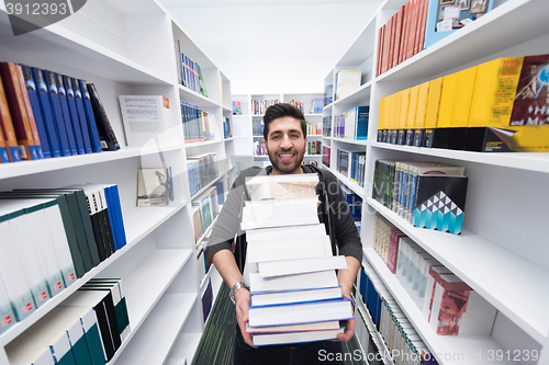 Image of Student holding lot of books in school library