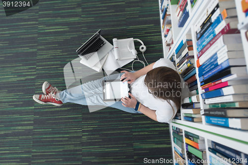 Image of female student study in library, using tablet and searching for 