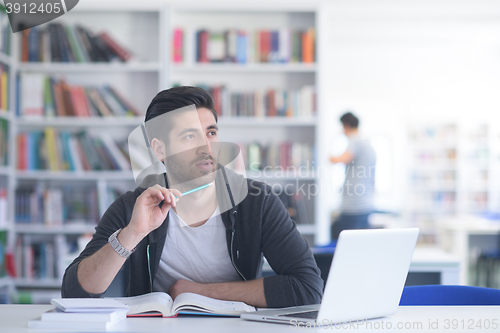 Image of student in school library using laptop for research