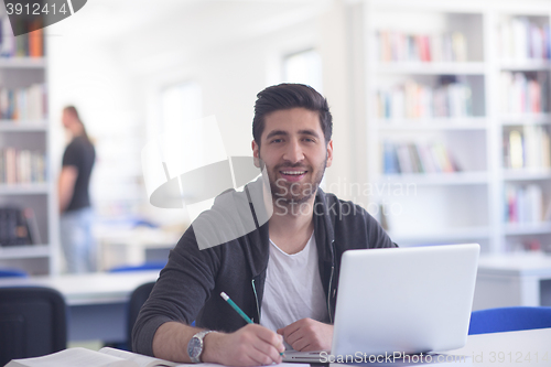 Image of student in school library using laptop for research