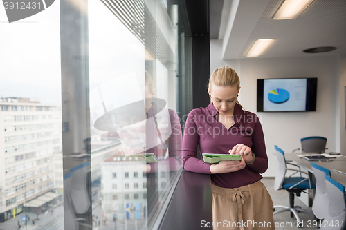 Image of blonde businesswoman working on tablet at office