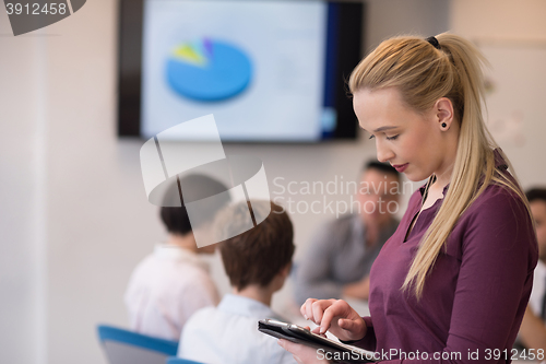 Image of blonde businesswoman working on tablet at office