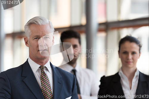 Image of portrait of senior businessman as leader  with group of people i