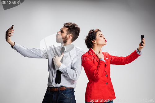 Image of Business concept. The two young colleagues holding mobile phones on gray background