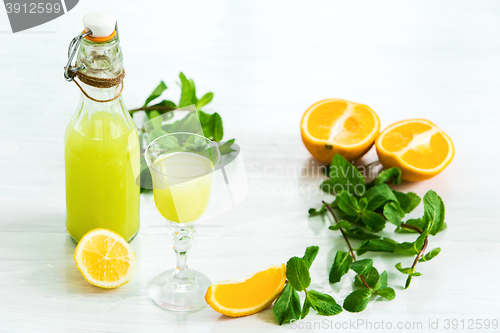 Image of Home orange liquor in a glass and fresh oranges on the white wooden background