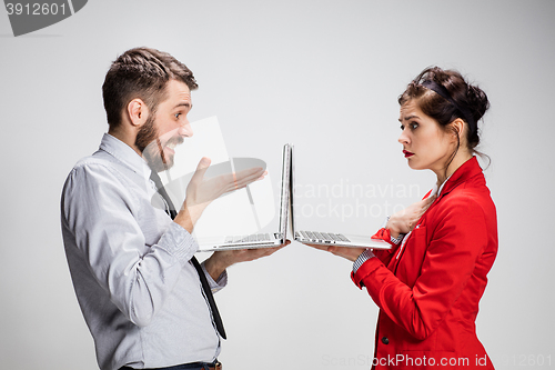 Image of The young businessman and businesswoman with laptops on gray background
