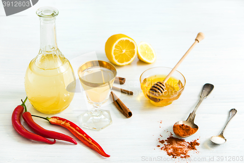 Image of Home red pepper tincture in a glass and fresh lemons on the white wooden background