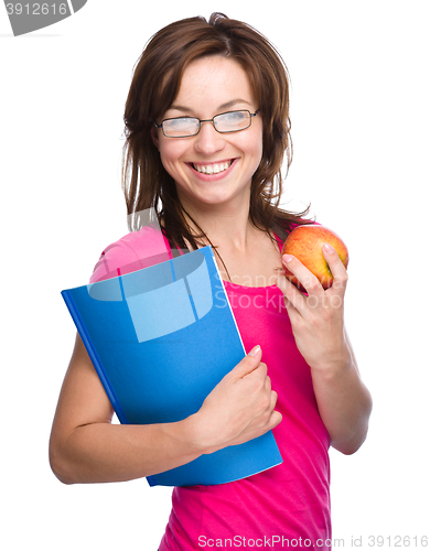 Image of Young student girl is holding book and apple