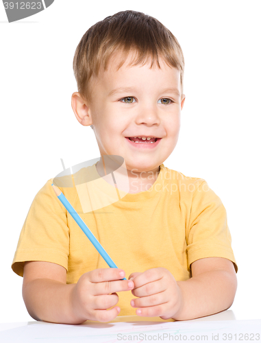 Image of Little boy is drawing using color pencils