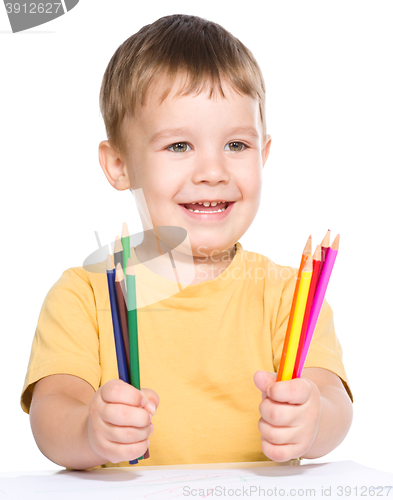 Image of Little boy is drawing using color pencils