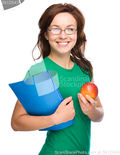 Image of Young student girl is holding book and apple