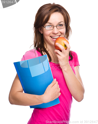 Image of Young student girl is holding book and apple