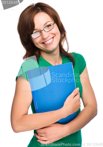 Image of Young skinny student girl is holding exercise book