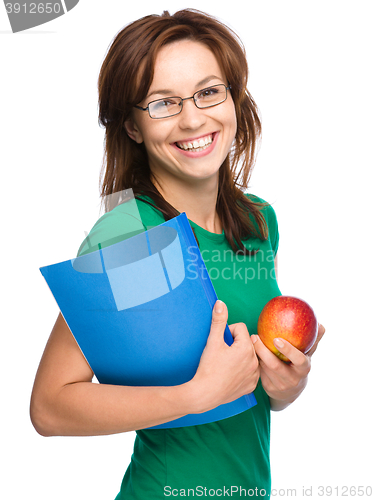 Image of Young student girl is holding book and apple