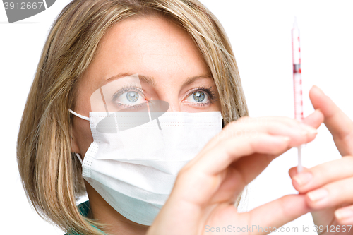 Image of Young nurse is preparing syringe for injection