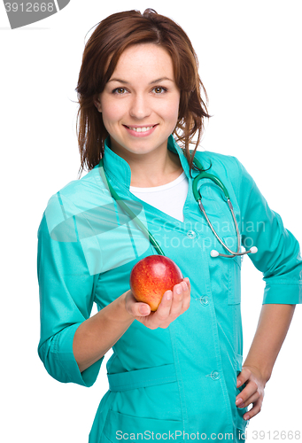 Image of Young lady doctor is holding a red apple