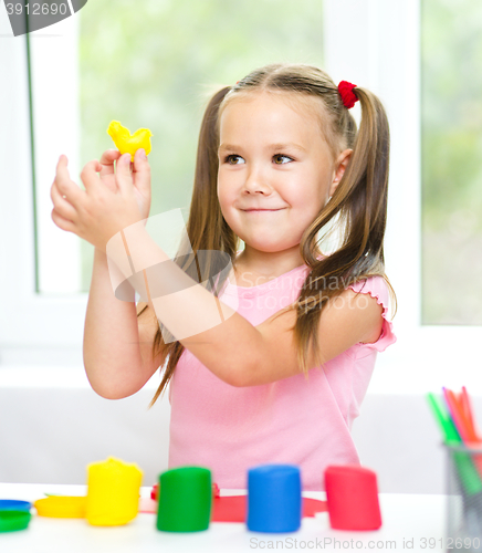 Image of Little girl is playing with plasticine