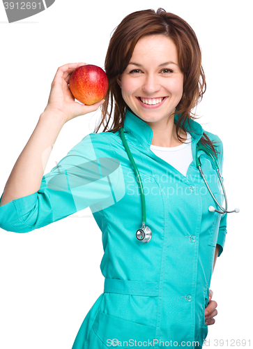 Image of Young lady doctor is holding a red apple