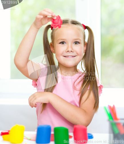 Image of Little girl is playing with plasticine