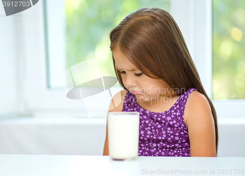 Image of Sad little girl with a glass of milk