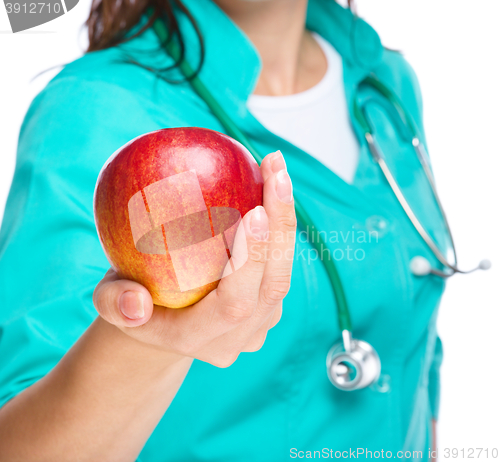 Image of Lady doctor is holding a red apple