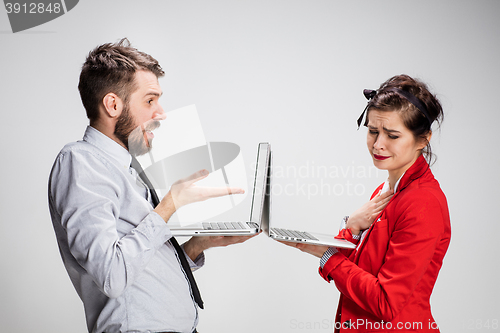 Image of The young businessman and businesswoman with laptops communicating on gray background