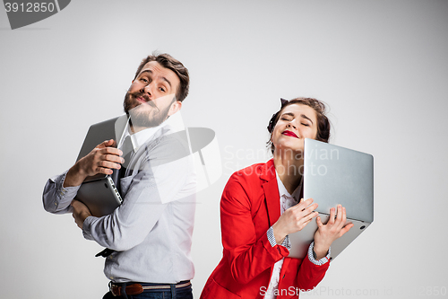 Image of The young businessman and businesswoman with laptops on gray background