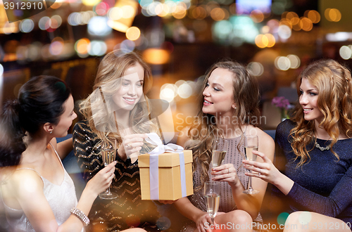 Image of happy women with champagne and gift at night club