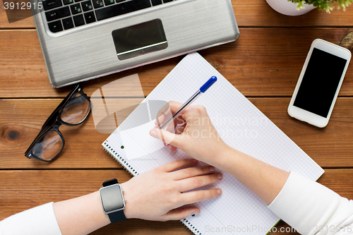 Image of close up of woman or student writing to notepad
