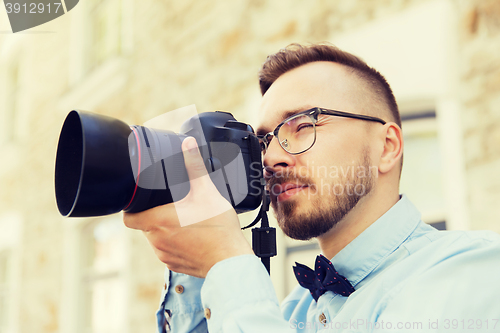 Image of young hipster man with digital camera in city