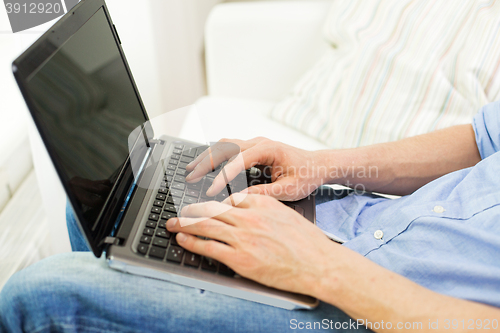 Image of close up of man typing on laptop computer at home