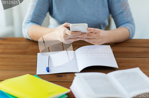 Image of close up of student with smartphone and notebook