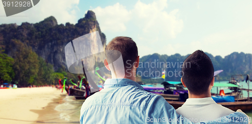 Image of close up of male gay couple hugging on beach