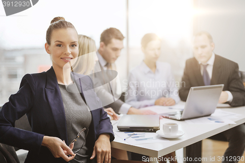 Image of businesswoman with glasses with team on the back