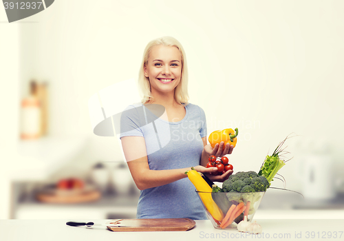 Image of smiling young woman cooking vegetables in kitchen 