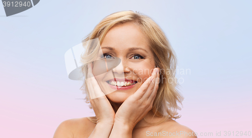 Image of smiling woman with bare shoulders touching face