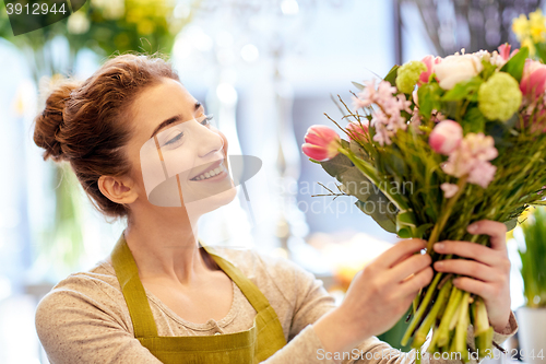 Image of smiling florist woman making bunch at flower shop