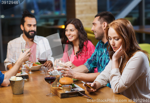 Image of woman with smartphone and friends at restaurant
