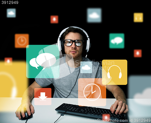 Image of man in headset with computer and icons on screen