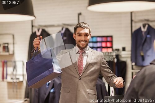Image of happy man with shopping bags at clothing store