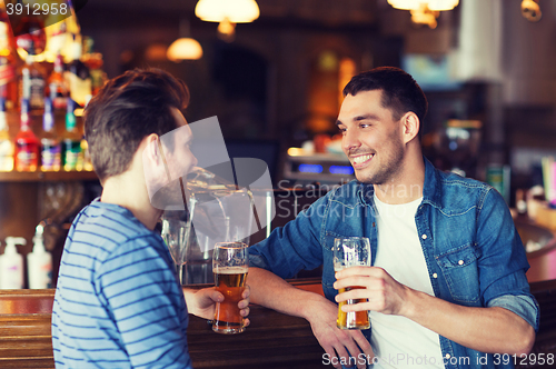 Image of happy male friends drinking beer at bar or pub