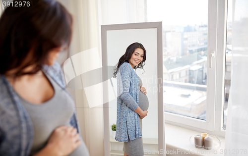 Image of happy pregnant woman looking to mirror at home