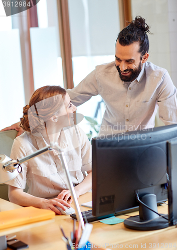 Image of happy creative team with computer in office