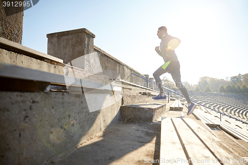 Image of happy young man running upstairs on stadium