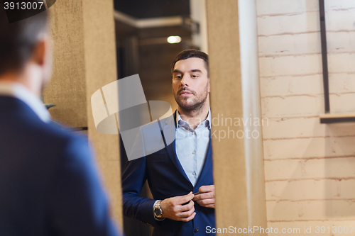 Image of man trying jacket on at mirror in clothing store